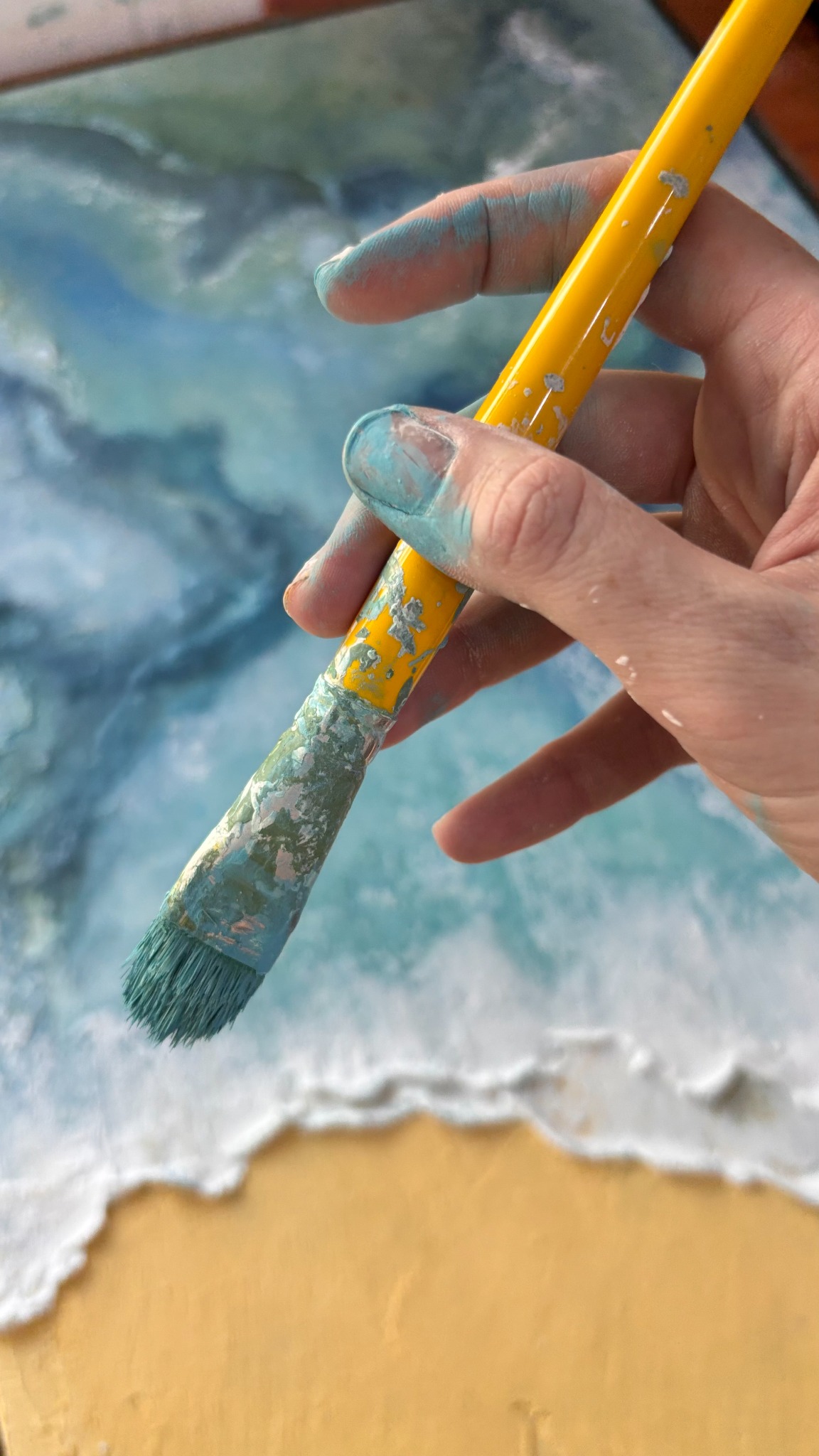 Mão com pincel durante a criação de uma obra com aquarela e texturas